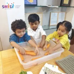 Children carefully wash carrots in a tub of water. This activity is part of our Exercises of Practical Life, which are designed to build independence and coordination.