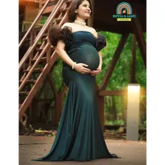 A portrait of strength and grace. The mom-to-be stands tall in a gorgeous teal gown, surrounded by the lush greenery of the park, showcasing the powerful beauty of pregnancy.