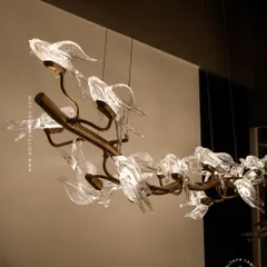 This horizontal chandelier features a flock of glass birds perched on a branch, as if in mid-flight. It's a perfect statement piece for suspension over a long dining table or in a living room, adding a dynamic and natural element.
