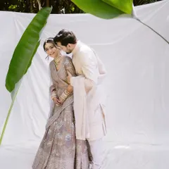 A serene and ethereal portrait. We used a simple white backdrop and a single banana leaf to create a minimal, artistic setting that highlights the couple's gentle connection.