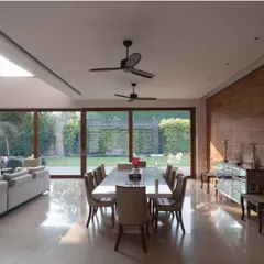 The expansive dining area seamlessly merges with the outdoors through floor-to-ceiling glass walls. This design choice floods the space with natural light and creates a constant dialogue between the interior and the lush landscape.