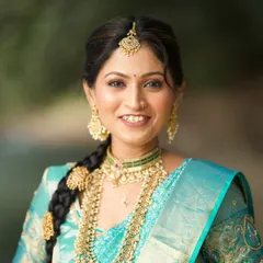 A close-up of the bride's happy face. Her makeup is fresh and radiant, highlighting her features while complementing the heavy gold jewelry.