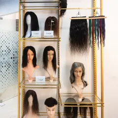 A display of various wigs and hair extensions at our studio. We offer solutions for everyone, including different lengths, colors, and styles, all made from 100% real human hair.