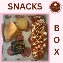 This snack box features a mix of hearty items including a samosa, a brownie, a cookie, and a hot dog, perfect for a party or casual corporate event.