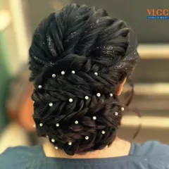 An elegant bridal updo featuring interwoven braids, sparkling glitter, and delicate pearl pins. This hairstyle is perfect for a reception or engagement ceremony.