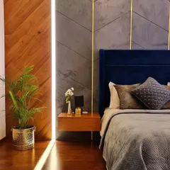 In this master bedroom, we blended multiple textures to create a warm and rich environment. The headboard wall features a combination of herringbone wood paneling and a grey textured surface with inlaid brass strips, set against a deep blue velvet bed frame.