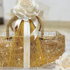 A full view of my mesh basket Diwali hamper, all packed and ready to go. The reusable golden basket is filled with tea cakes and jars of salted nuts, wrapped in delicate mesh with a beautiful flower on top.