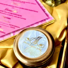 A close-up of a personalized jar lid, showing the couple's initials in elegant gold calligraphy. This small detail adds a significant touch of personalization to the hamper, making your guests feel truly special.