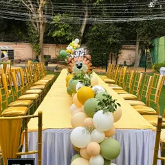 The safari theme extends to the guest tables with a long, flowing balloon runner. This table centerpiece incorporates animal-shaped balloons and matching colors, making the entire party space feel cohesive and fun.
