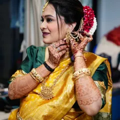 A classic shot of the mom-to-be adjusting her beautiful temple jewelry. The makeup is traditional and elegant, perfect for this important cultural ceremony.