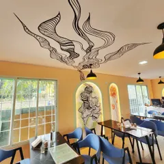 This view of Essence Cafe shows how our wall-to-ceiling art installation interacts with the space's lighting and layout. The flowing black lines add movement and visual interest above the dining tables.
