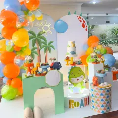 ROAR! Our dinosaur theme parties are a blast of color and fun. This setup shows a complete dessert station with a custom 'ROAR' light-up sign, adorable dino cutouts, and a vibrant balloon garland, perfect for a prehistoric adventure.