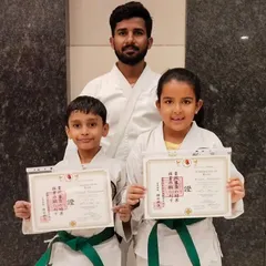 Hard work pays off. These two students proudly display their new green belt certificates, a significant milestone in their karate training that reflects their growing skill and discipline.