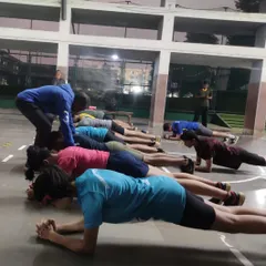 A coach provides hands-on correction during a plank exercise. We stress the importance of perfect posture to maximize core engagement and prevent strain, which is critical for all athletic movements.