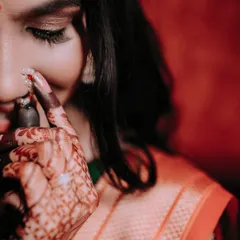 A detailed close-up shot focusing on the bride's intricate mehendi and her traditional nath (nose ring). This type of photo highlights the small but important details of the bridal look.