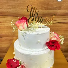 I believe every love story deserves a beautiful cake. This is a two-kilogram, two-tier Dutch Truffle engagement cake, decorated with fresh roses and baby's breath to mark the couple's special "It's Official!" moment.