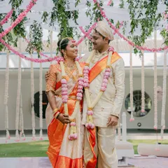 A portrait of the couple during their Muhurtham. The bride's Kanjeevaram saree and the groom's veshti are complemented by beautiful lotus garlands, a key element of our floral design.