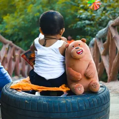 A candid shot from behind during the "little mechanic" session, showing the baby interacting with his teddy bear companion. This perspective adds a story-telling element to the themed baby photoshoot.