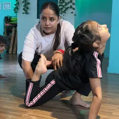 Correcting posture during a backbend. This hands-on approach helps students understand the feeling of proper alignment, which is crucial for advanced moves and injury prevention.