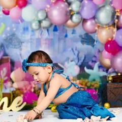 This little mermaid is exploring her under-the-sea kingdom. I designed this entire set with a castle backdrop, colorful balloons, and seashells for her first birthday.