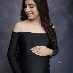 A fitted black gown can create a stunningly elegant and modern maternity portrait. This off the shoulder, mermaid style dress beautifully accentuates her form, while her gentle smile adds a touch of warmth.