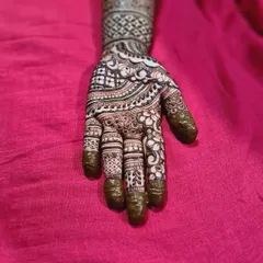 A beautiful henna design for a baby shower, featuring intricate patterns on the hand and a clean, banded design on the arm.
