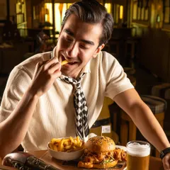 A man enjoying a burger and fries at a pub. This candid moment feels authentic and captures the simple pleasure of good food.