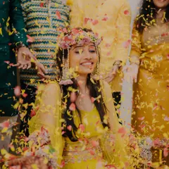 A radiant bride enjoying a shower of colorful petals during her Haldi ceremony, her smile lighting up the entire frame.