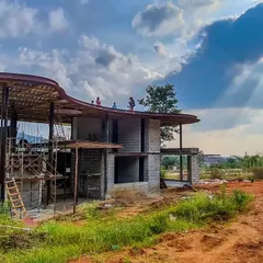 A blessed abode taking shape under the sun's rays. This image captures the raw beauty of the construction process, where the quirky curve of the roof begins to interact with the sky, hills, and earth.