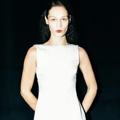 A striking portrait of a model backstage at LFW. The high-contrast lighting and dark background create a dramatic and intense look.