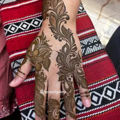 A beautiful Arabic-style floral vine design on the back of the hand. The pattern flows organically from the wrist to the fingers, using shading to give the flowers and leaves a 3D feel.