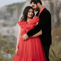 A beautiful portrait where the groom-to-be holds his partner tenderly. Her red gown provides a stunning pop of color against the natural, muted tones of the field.