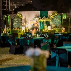 Another perspective of the outdoor lawn setup, showing the arrangement of tables and the beautifully lit stage in the background, ready for an evening of celebration.