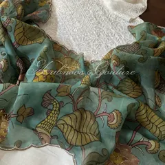This ensemble showcases a unique artistic fusion, pairing a classic off-white Chikankari suit with a stunning Srikalahasti Kalamkari organza dupatta. The hand-painted dupatta features delicate highlights and scalloped edging, creating a beautiful dialogue between two revered crafts.
