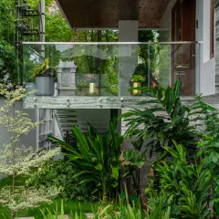 This design showcases a perfect blend of architecture and landscape. A glass-railed balcony overlooks a densely planted garden, creating a harmony between the clean lines of the home and the organic forms of nature.