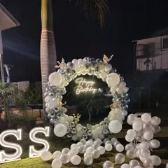 This elegant outdoor birthday decoration is perfect for evening parties. The combination of a chrome balloon wreath, a bright neon sign, and large marquee letters creates a stunning focal point on the lawn.