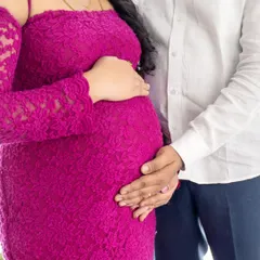 A detailed shot of a couple's hands cradling the baby bump, showing the texture of the mom's beautiful lace dress.