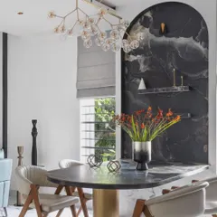 For Dr. Harsha's home, we created a dramatic dining nook with a custom-built table integrated into a monolithic dark tile wall. This space-saving solution becomes a bold statement piece, contrasting beautifully with the home's otherwise light and airy feel.