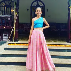 For a modern twist on a traditional outfit, I designed this one-shoulder crop top in a bright, textured blue fabric. Paired with a pink and gold patterned skirt, it creates a unique and stylish look for any festive occasion.