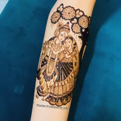 A classic Radha-Krishna portrait under a tree, drawn on the forearm. This kind of divine figure work is a beautiful addition to any bridal mehendi.