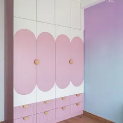 For this child's room, we designed a playful wardrobe with pink scalloped panels and simple wooden knobs. The design is whimsical yet functional, with ample drawer storage below for toys and clothes.