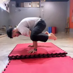 An adult student holds a perfect Bakasana, or Crow Pose, on the mats. This is a great example of the calisthenics and bodyweight strength training we focus on in my gymnastics sessions to improve balance and core power.