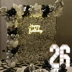 A chic and modern party backdrop featuring a silver shimmer wall and a black, white, and silver balloon arrangement. While this setup displays a "Happy Birthday" sign and the number 26, I can customize it for any anniversary with the right text and numbers.