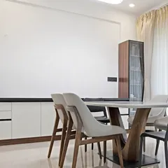 This dining space is designed for easy conversations and everyday comfort. The mix of light and dark tones, a clean-lined crockery unit, and soft natural light make it both stylish and functional.