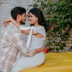 A romantic and playful moment with the mother-to-be sitting on the hood of a vintage car, embracing her partner.