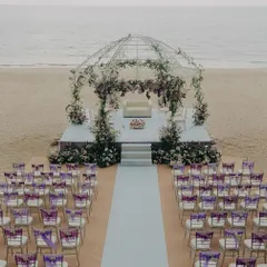 The stunning beachside mandap setup in Khao Lak, Thailand, just before the ceremony. This wide shot showcases the beautiful decor and the serene ocean backdrop, setting the scene for a dream wedding.