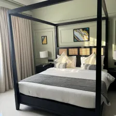A different view of the modern black canopy bed, highlighting its clean lines and minimalist frame. The matching nightstands and lamps create a symmetrical and balanced look for a sophisticated guest room.