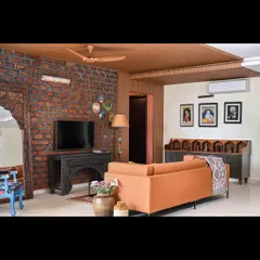 A wide view of the family lounge in our "Colors of Goa" project, showing how the rustic brick wall, wooden ceiling, and bespoke bar unit come together to create an earthy and stylish space.