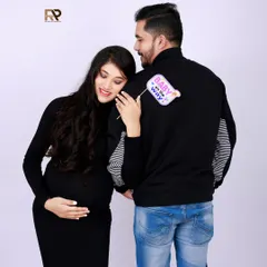 A playful and cute announcement. The mom-to-be holds a "Baby on the way" sign, leaning against her partner in this sweet and modern couple's shot.