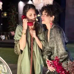 Capturing candid moments of connection and fun. Two guests share a laugh while leaving a joint message, showcasing the interactive and social nature of the audio guestbook experience at an evening sangeet or reception.